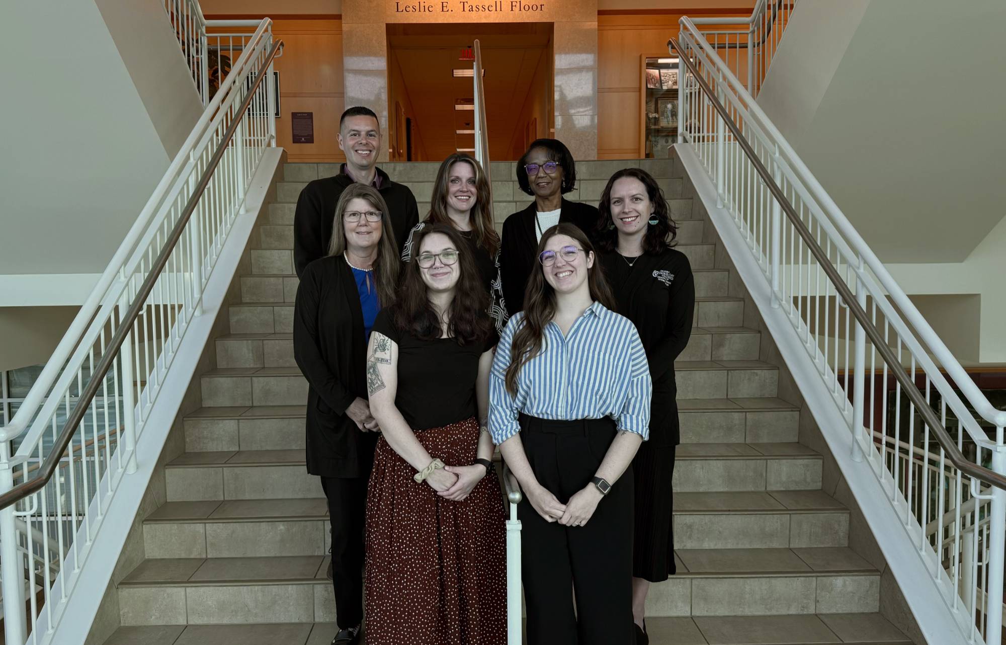 Group photo of CHP Student Services Office standing on a staircase in the Center for Health Sciences building
